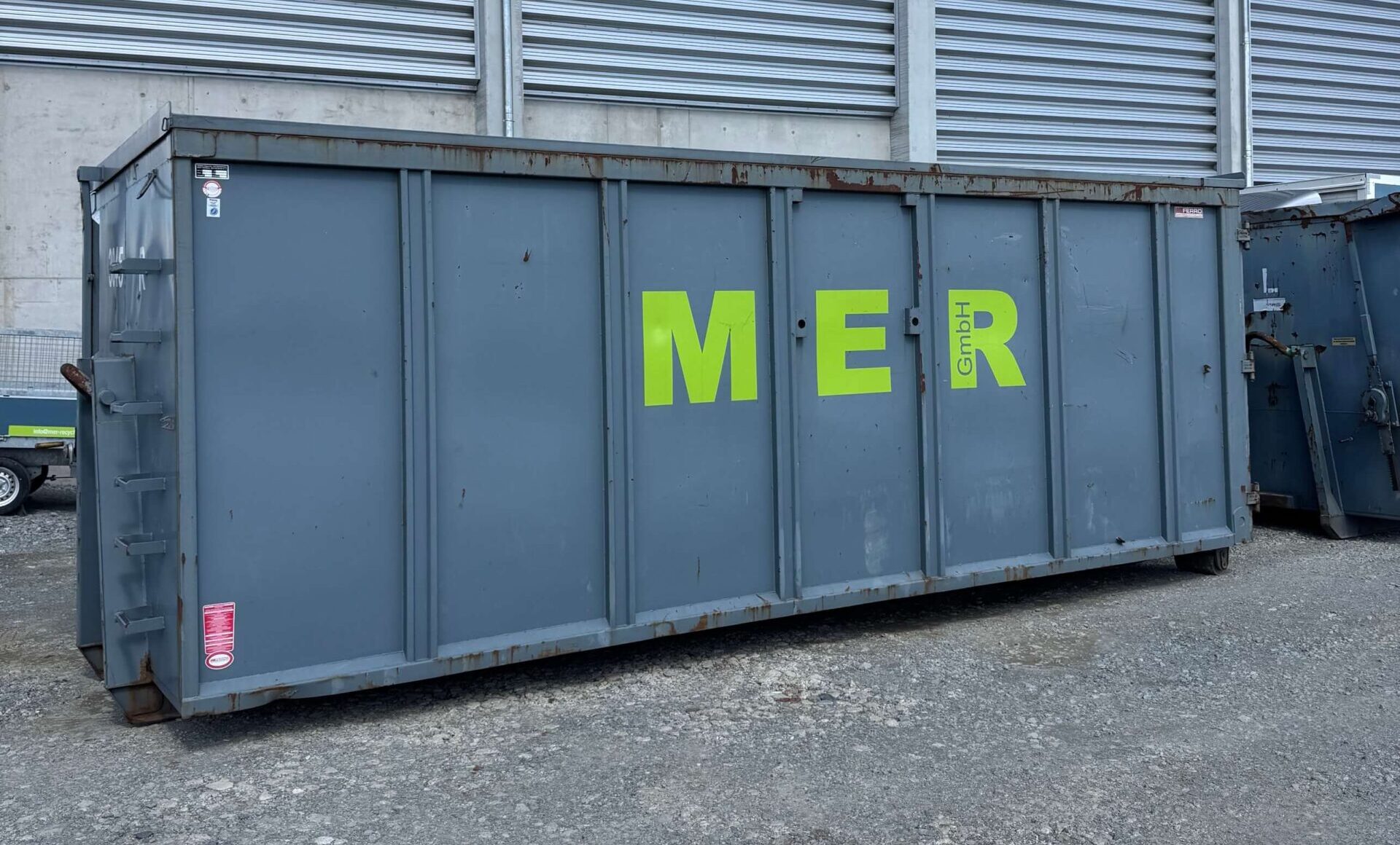 Abrollcontainer steht vor einer Halle